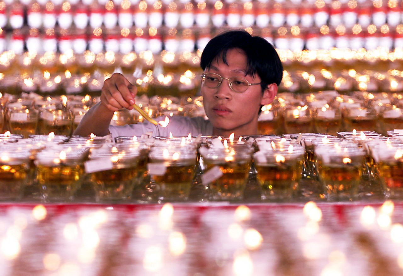 A devotee lights one of the 5,000 oil lamps at a Buddhist temple in Kuala Lumpur on May 29, 1999, as a gesture to bring light to his life on Wesak Day. – AFP pic