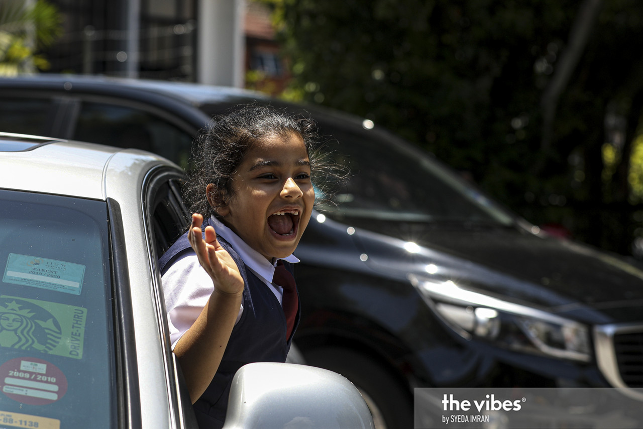 An SK Seri Hartamas pupil waves outside a car window after school ends for the day. – SYEDA IMRAN/The Vibes pic, March 8, 2021