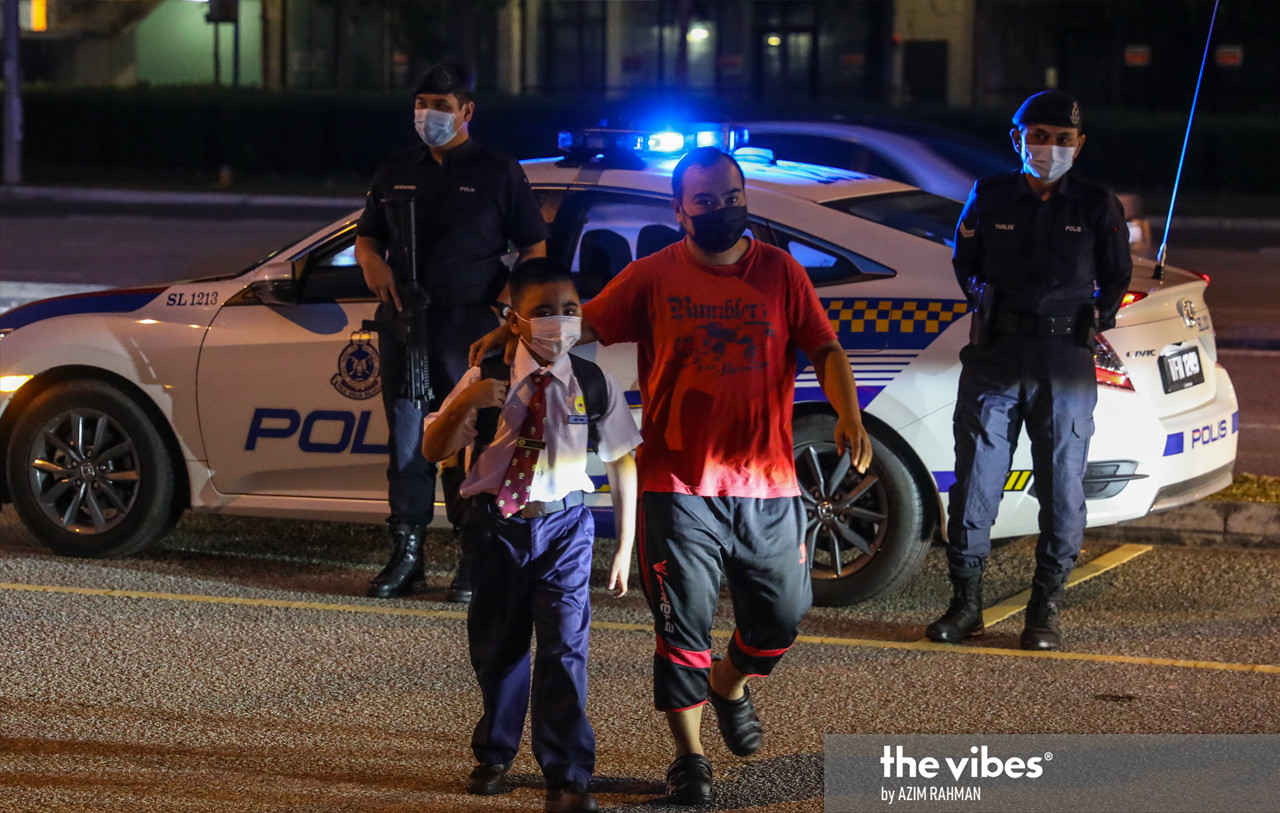 Police stand guard as a pupil is escorted by his guardian at SK Cyberjaya. – AZIM RAHMAN/The Vibes pic, March 8, 2021