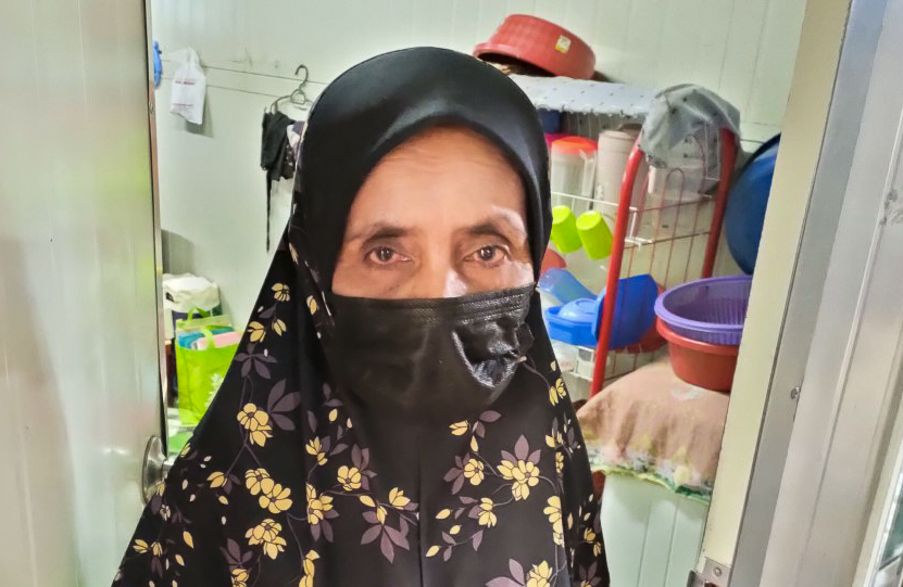 Aidah Jaujani, 55, bathes on the walkway in front of her container home using water collected from a pipe near the shared toilets. – REBECCA CHONG/The Vibes pic, March 29, 2021