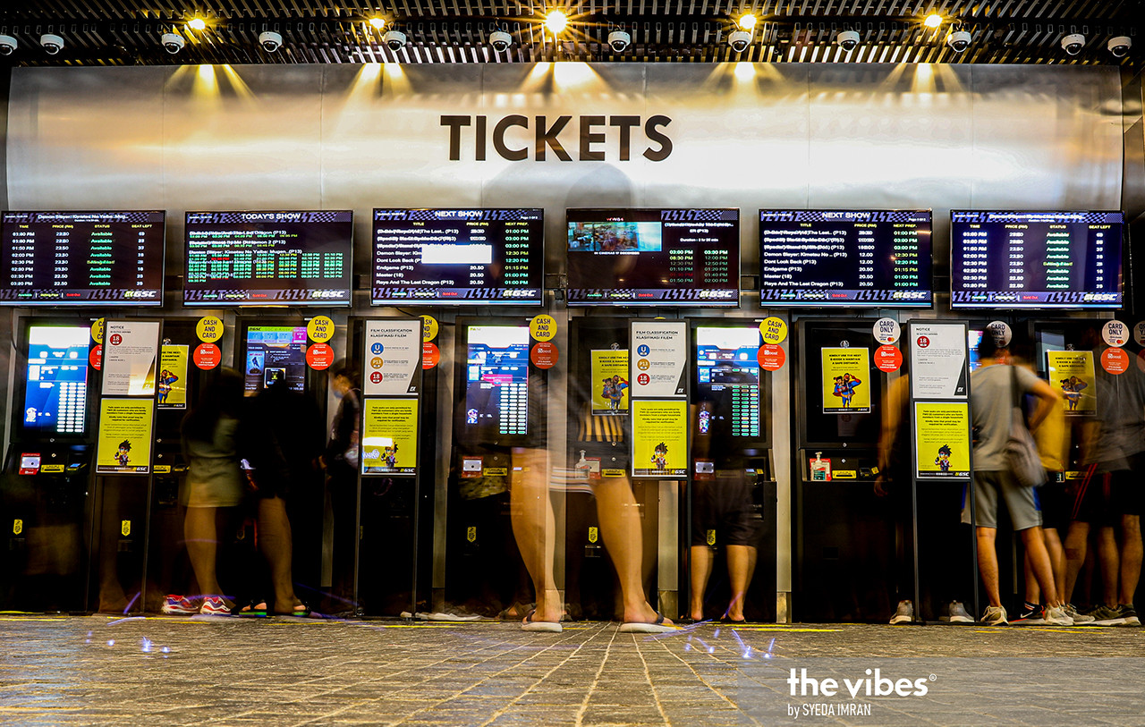 Monitors showing what movies are playing today, while customers queue in front of ticket booths. – SYEDA IMRAN/The Vibes pic, March 6, 2021