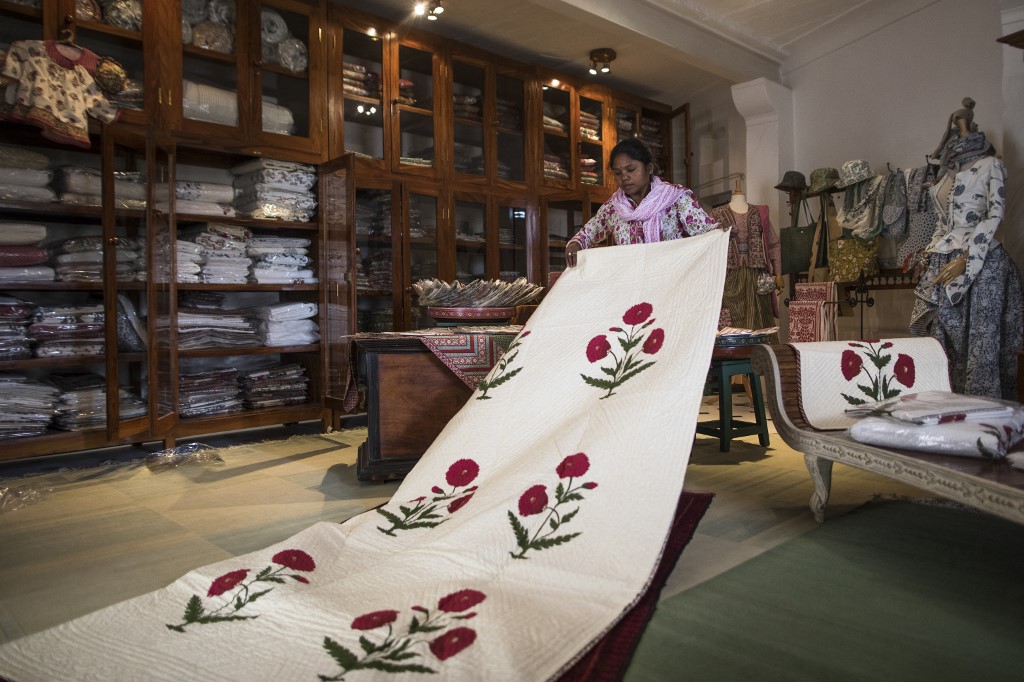 In this picture taken on June 3, a worker displays a quilt with a hand block printing design of a poppy flower, reedited from an original design of the 17th century made for Mughal emperor Shah Jahan, at the shop of textile Indian naturalised designer Brigitte Singh in Amber on the outskirts of Jaipur in India's Rajasthan state.