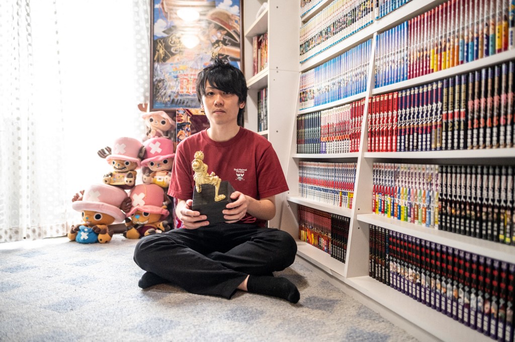 In this picture taken on September 18, Shohei Sato poses a photo with a trophy from the One Piece knowledge king contest after an interview with AFP in his house in Tokyo. – AFP pic