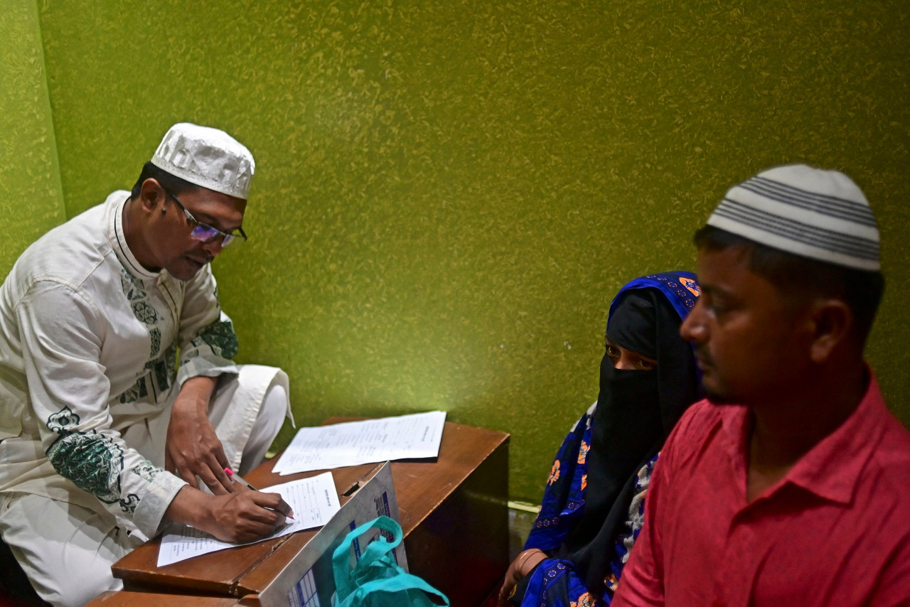 A shrine official prepares a checklist for Ferdousi Begum (C), who consulted Sufi leader Syed Emdadul Hoque (not pictured), at the Maizbhandar Darbar Sharif shrine in Maizbhandar. – AFP pic