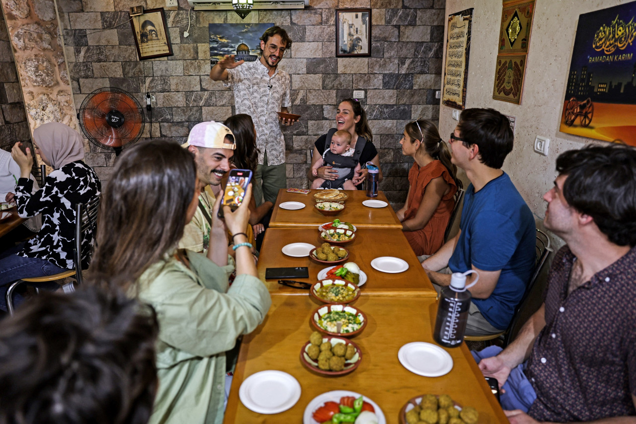 Tour guide Izzeldin Bukhari (C), who runs Jerusalem food tours and cooking classes, presents dishes to tourists in a restaurant during a guided tour in the Old City. – AFP pic