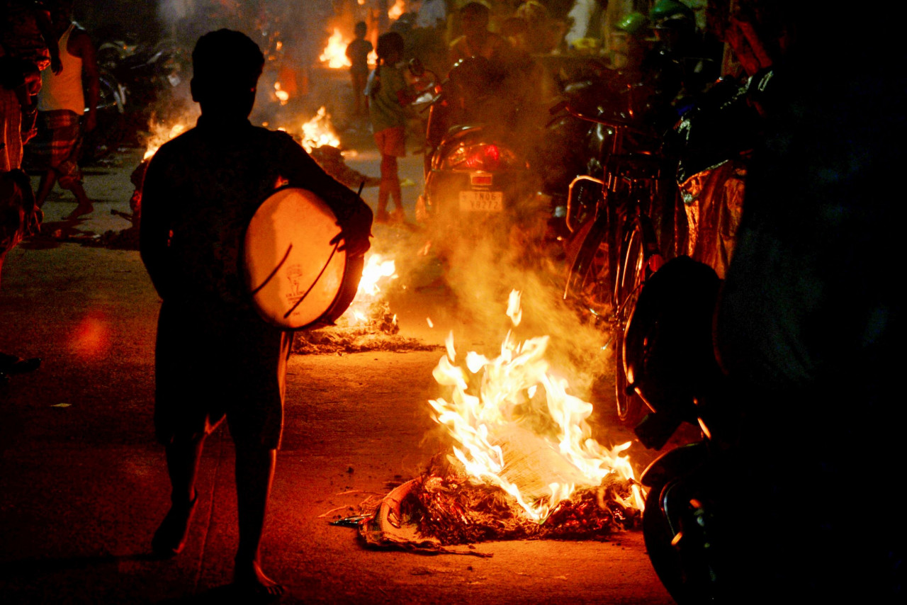A boy plays the drum beside bonfires on the eve of the Hindu harvest festival of Ponggal in Chennai, India. – AFP pic