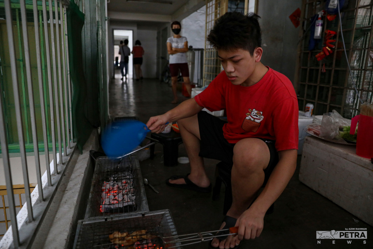 Twenty-year-old Yong Kien Tung helps his mom with the kitchen duties by watching over the barbeque area. — The Vibes/Azim Rahman pic