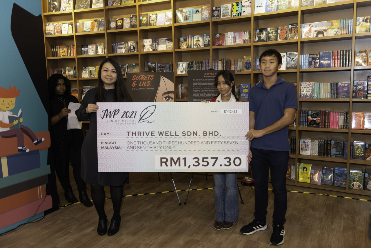 Helena Aysera Hishamuddin Hud and Zizou Looi of Junior Writers 2021 present the mock cheque to Thrive Well's Michelle Lim. – Pic courtesy of Junior Writers Programme