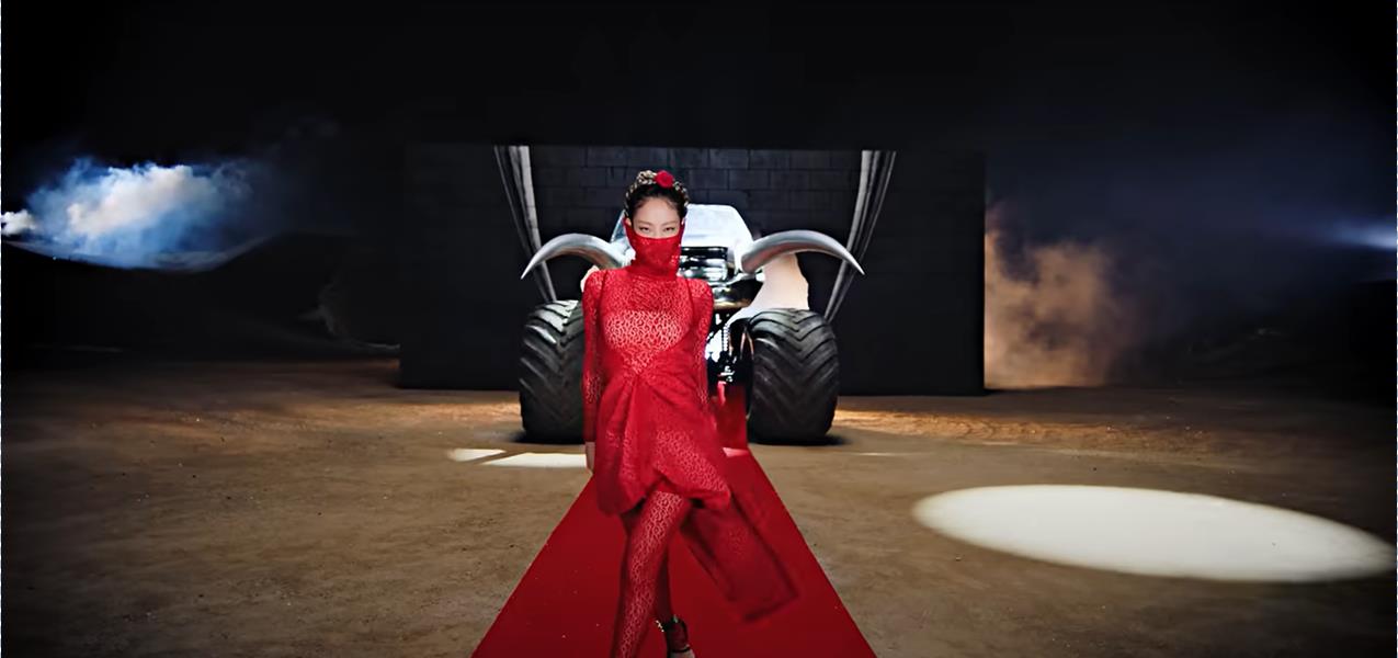 Jennie with a monster truck behind her in the second scene of Pink Venom. – YouTube screengrab