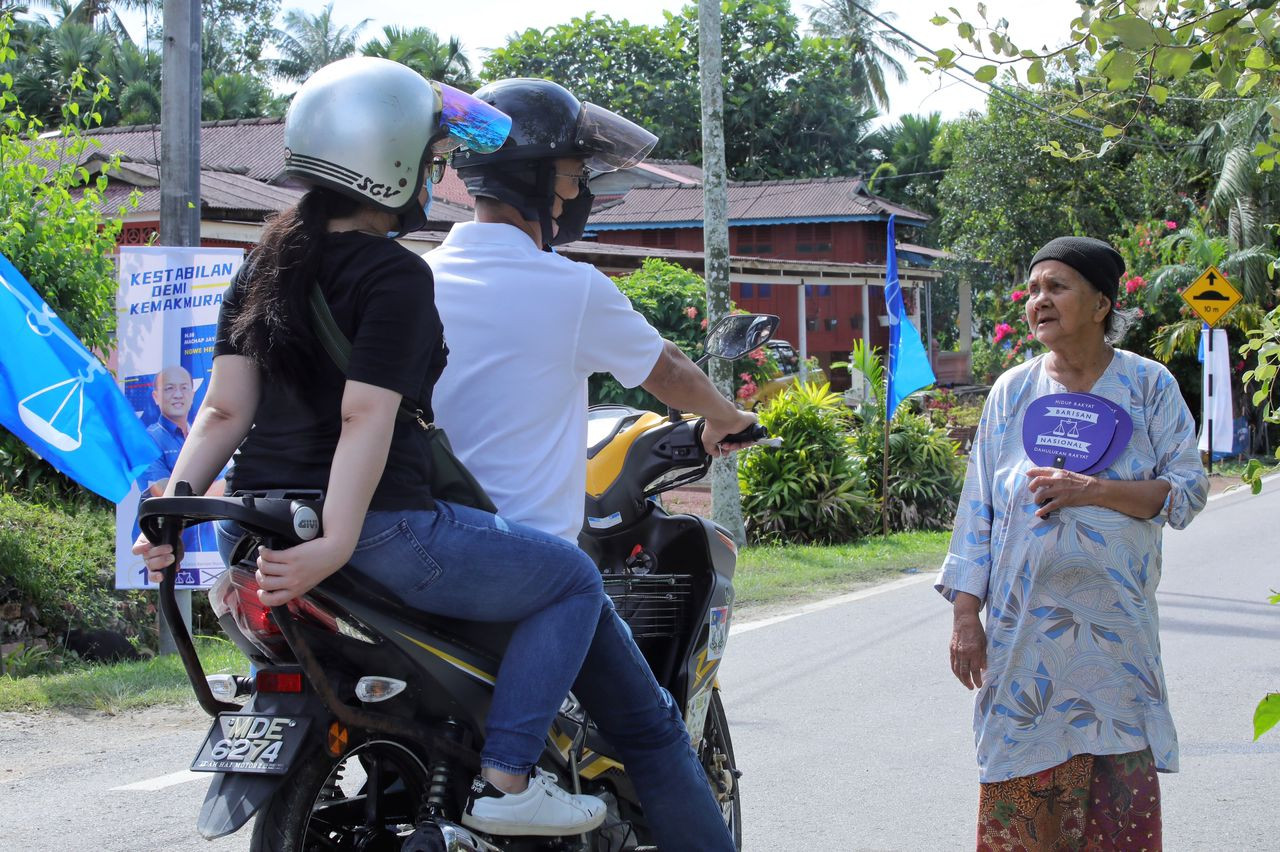 Barisan Nasional candidate for Machap Jaya, Ngwe Se Hem, taking his daughter to visit Kg Bulat and meet voters on a motorcycle. – MCA pic, November 19, 2021