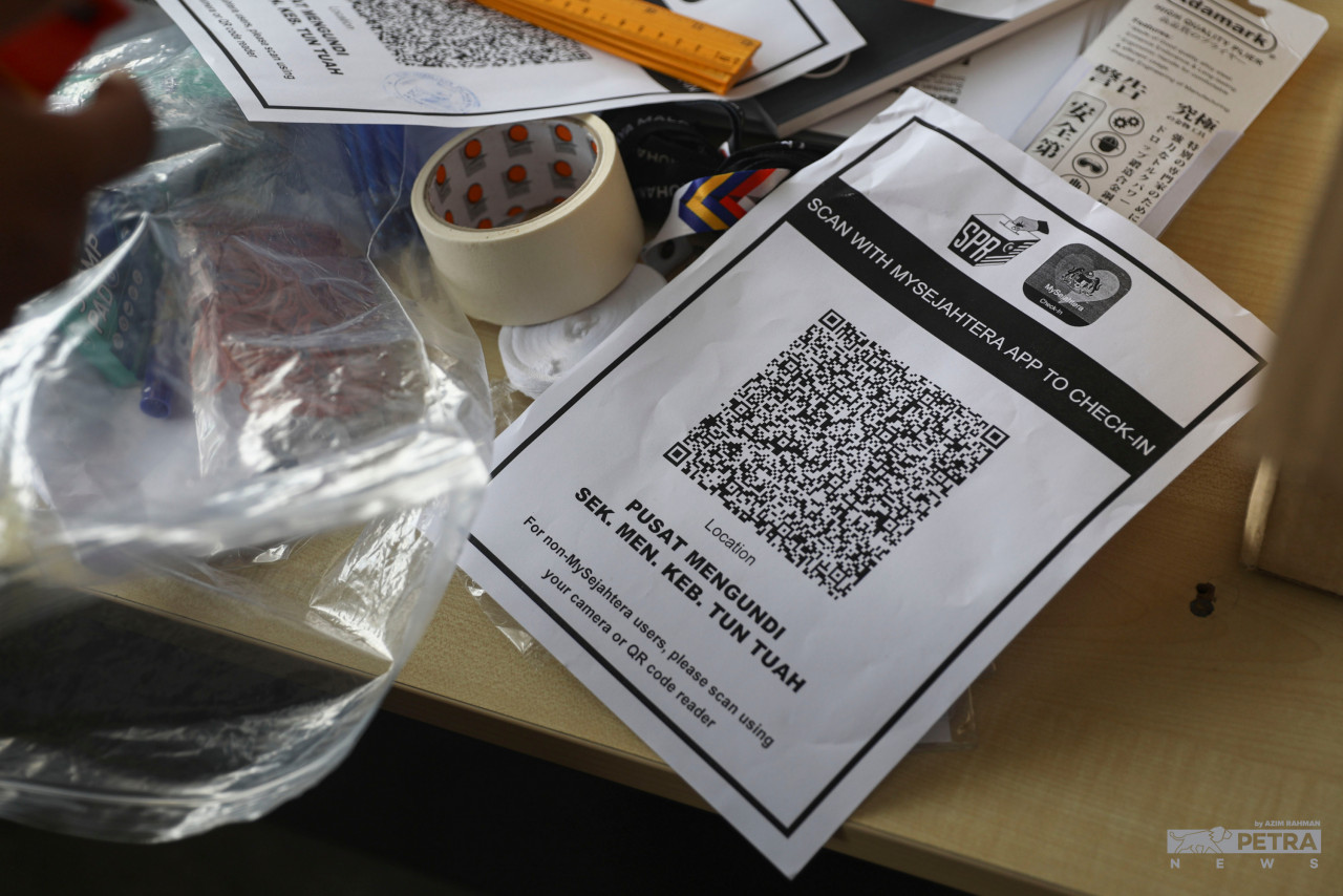 Voters need to scan MySejahtera QR codes before they can enter the premises to cast their votes. – AZIM RAHMAN/The Vibes pic, November 19, 2021