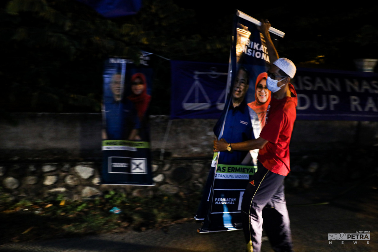 Putting up political party flags at night is a time-honoured tradition for party volunteers. – ALIF OMAR/The Vibes pic, November 9, 2021
