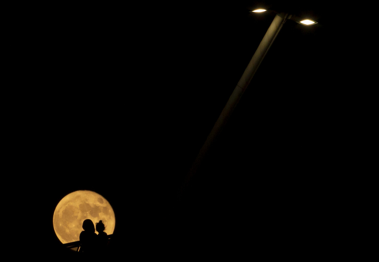 A woman holding a child as they watch the full moon rise over the southern Iraqi city of Basra. – HUSSEIN FALEH/AFP pic, October 8, 2021