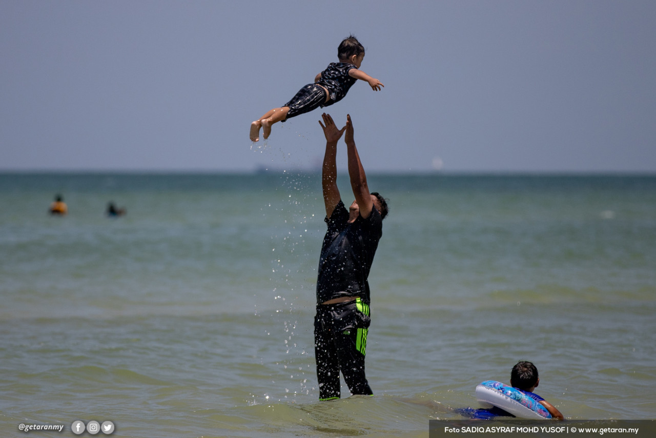 A father playing with his son at Teluk Kemang beach. – Getaran pic