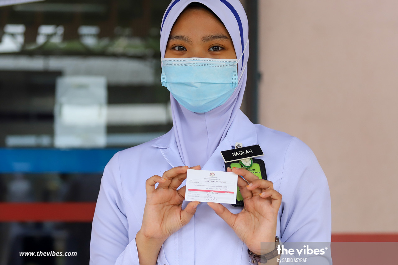 A health worker holding up her vaccination card after receiving the inoculation at HKL yesterday. – SADIQ ASYRAF/The Vibes pic, March 2, 2021