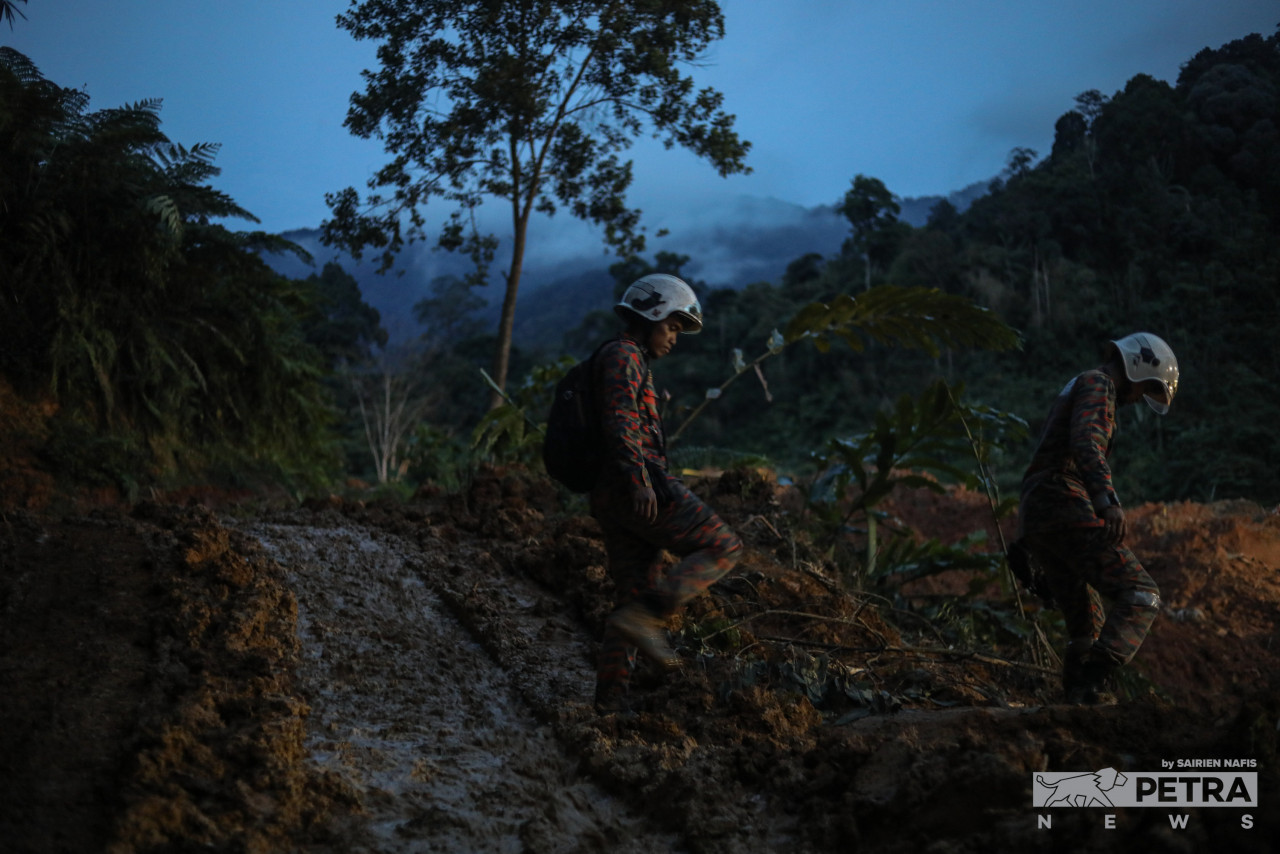 Rescuers make their way through waterlogged soil and muddy conditions yesterday as they head for the scene of the Batang Kali landslide. – SAIRIEN NAFIS/The Vibes pic, December 21, 2022