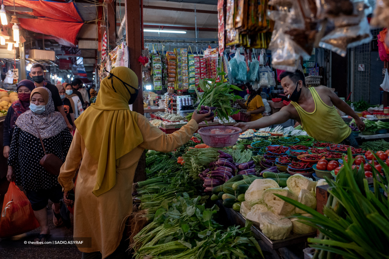 Separated from a seller by a wide variety of vegetables, a customer passes her chosen purchases into a waiting basket. – SADIQ ASYRAF/The Vibes pic, October 2, 2021