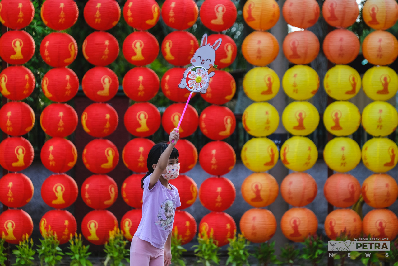 Against a backdrop of red, orange, and yellow lanterns at the FGS Dong Zen Temple in Kg Jenjarom, Selangor, a little girl cheerfully holds up a rabbit-themed fan. – ABDUL RAZAK LATIF/The Vibes pic, January 21, 2023