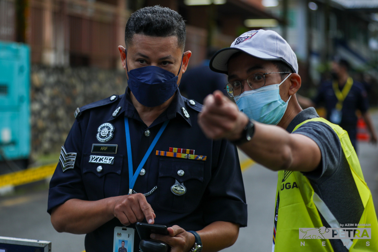 A polling officer gives pointers to a police officer who arrives at the Bukit Aman police headquarters to cast an early ballot today. Main polling day will take place this Saturday, November 19. – AZIM RAHMAN/The Vibes pic, November 15, 2022