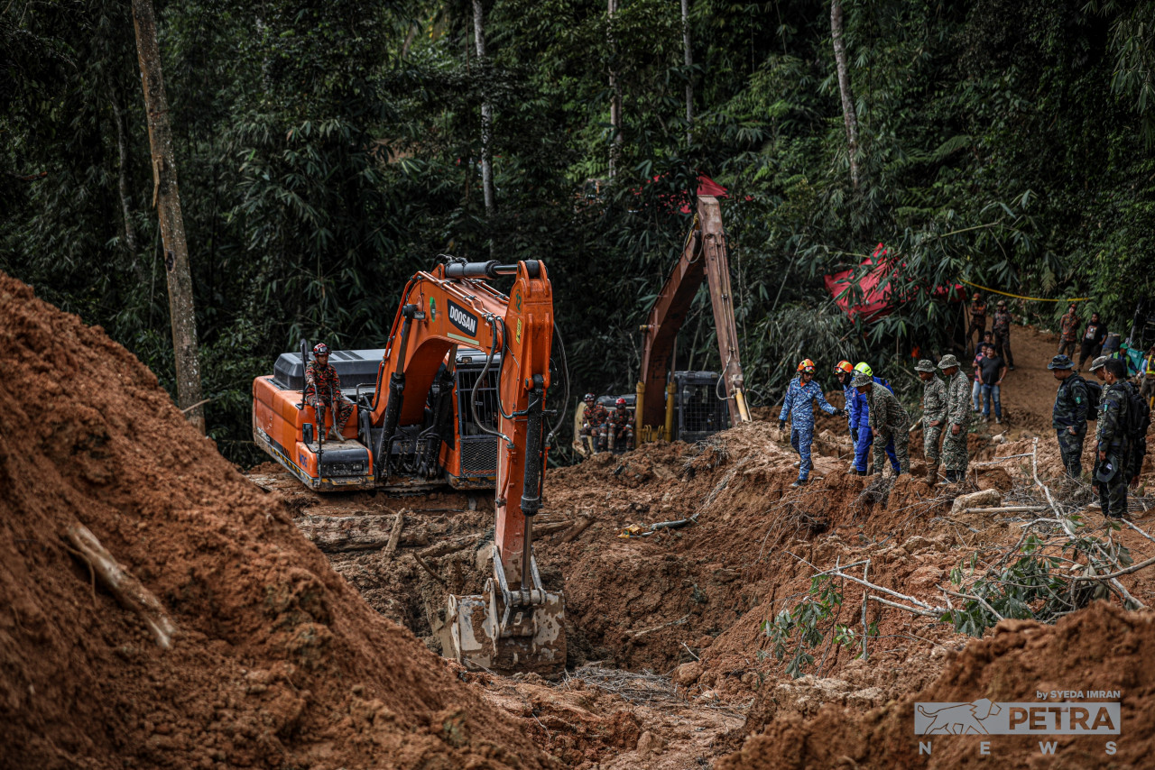 Rescuers discuss their next move next to a Fire and Rescue Department member operating an excavator. – SYEDA IMRAN/The Vibes pic, December 19, 2022