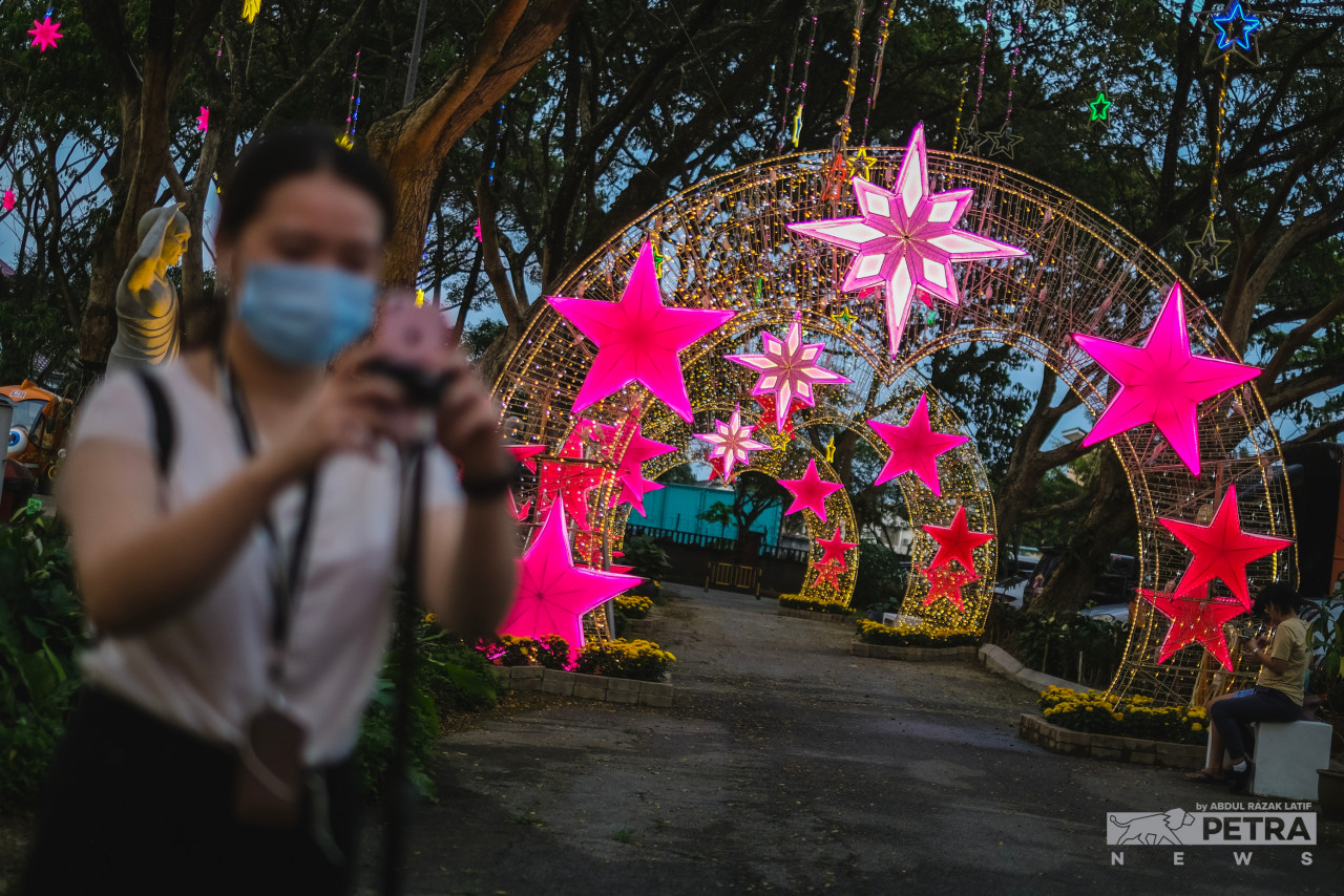 In the foreground, a visitor takes photographs at the FGS Dong Zen Temple. Spectacular arches adorned with bright pink stars and tiny yellow lights can be seen behind her. – ABDUL RAZAK LATIF/The Vibes pic, January 21, 2023