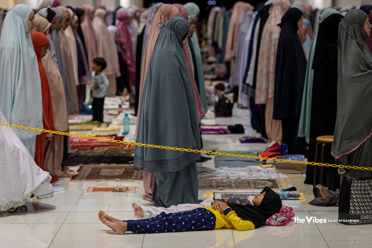 Appearing to be asleep, an exhausted child lies down as adults carry out tarawih prayers at Masjid Tuanku Mizan Zainal Abidin in Putrajaya. – AZIM RAHMAN/The Vibes pic, March 23, 2023
