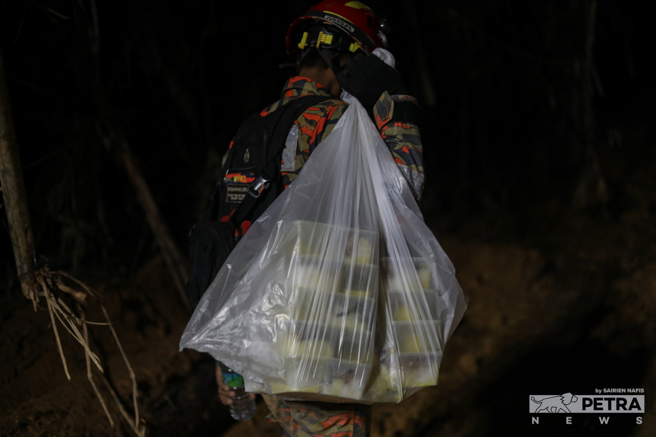 A rescuer carries food for his fellow search-and-rescue team personnel. The team has had its meals delivered to allow them to search for the remaining victims of the Batang Kali landslide. – SAIRIEN NAFIS/The Vibes pic, December 21, 2022