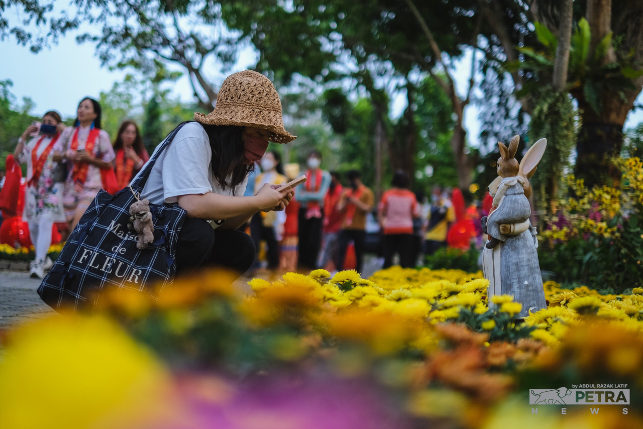 A visitor takes photographs of flowers at the FGS Dong Zen Temple, among which stands a small rabbit display. – ABDUL RAZAK LATIF/The Vibes pic, January 21, 2023