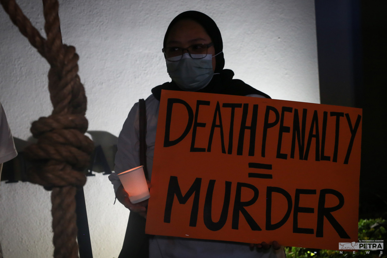 A vigil attendee holds up a sign equating the death penalty to murder. Some attendees say those who end up being executed for drug offences are merely victims of circumstance. – NOOREEZA HASHIM/The Vibes pic, July 6, 2022