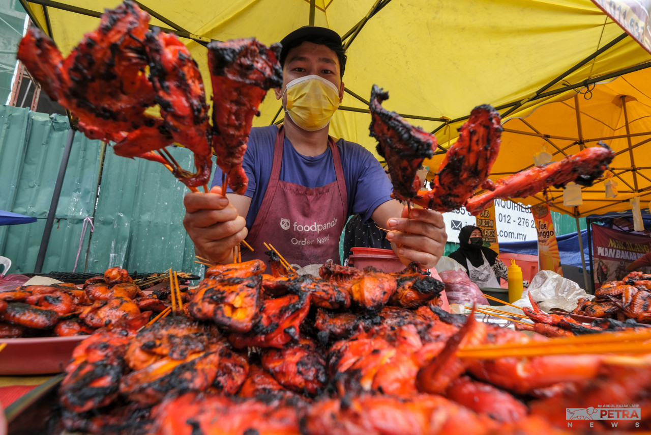 Muhammad Yazid Saufi showing the sticks of honey ayam percik he has for sale at the stall he shares with his wife Samsiah Saifuddin. – ABDUL RAZAK LATIF/The Vibes pic, April 9, 2022