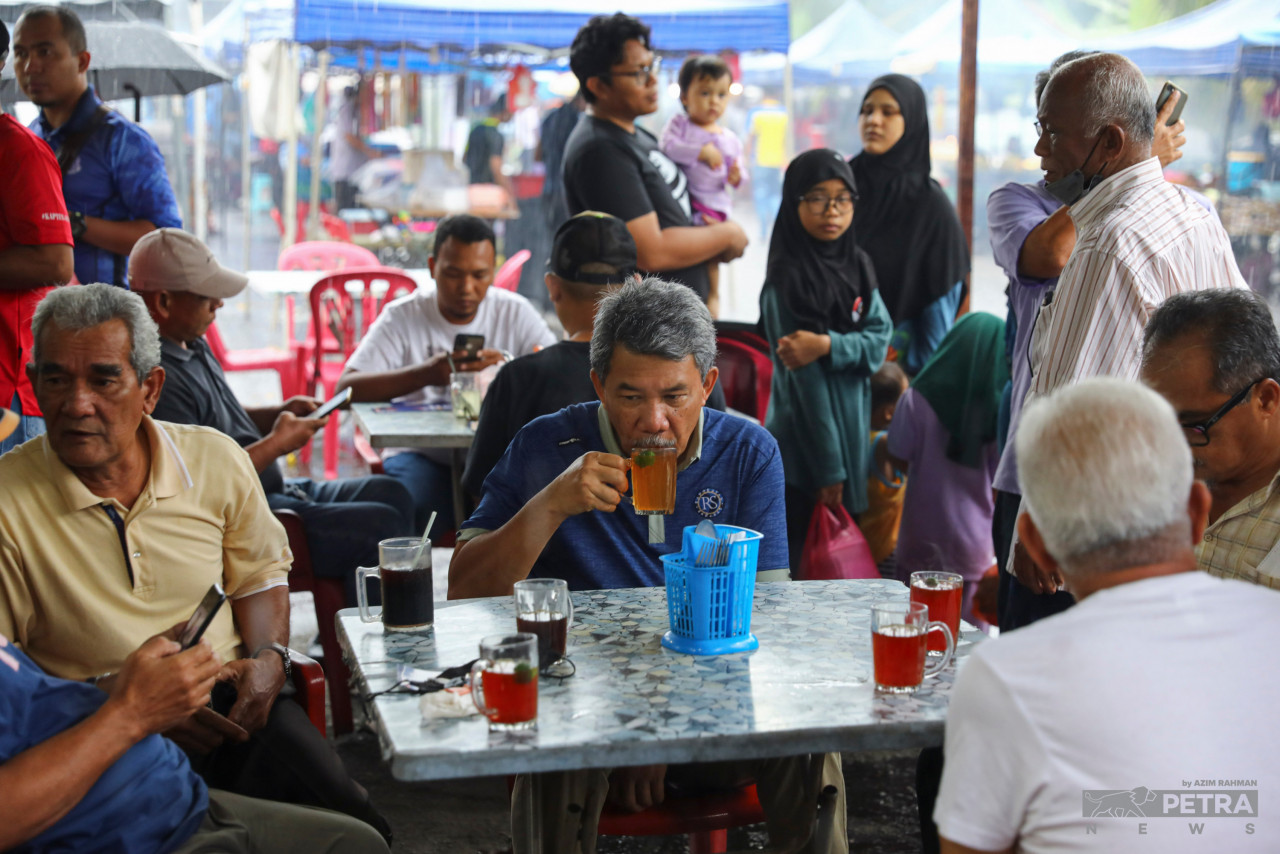 Datuk Seri Mohamad Hasan visits a food stall for a cup of hot lime tea at the night market in Taman Tuanku Jaafar, Senawang. He said that so far, he has only spent money on food for the people who are volunteering for his campaign. – AZIM RAHMAN/The Vibes pic, November 9, 2022