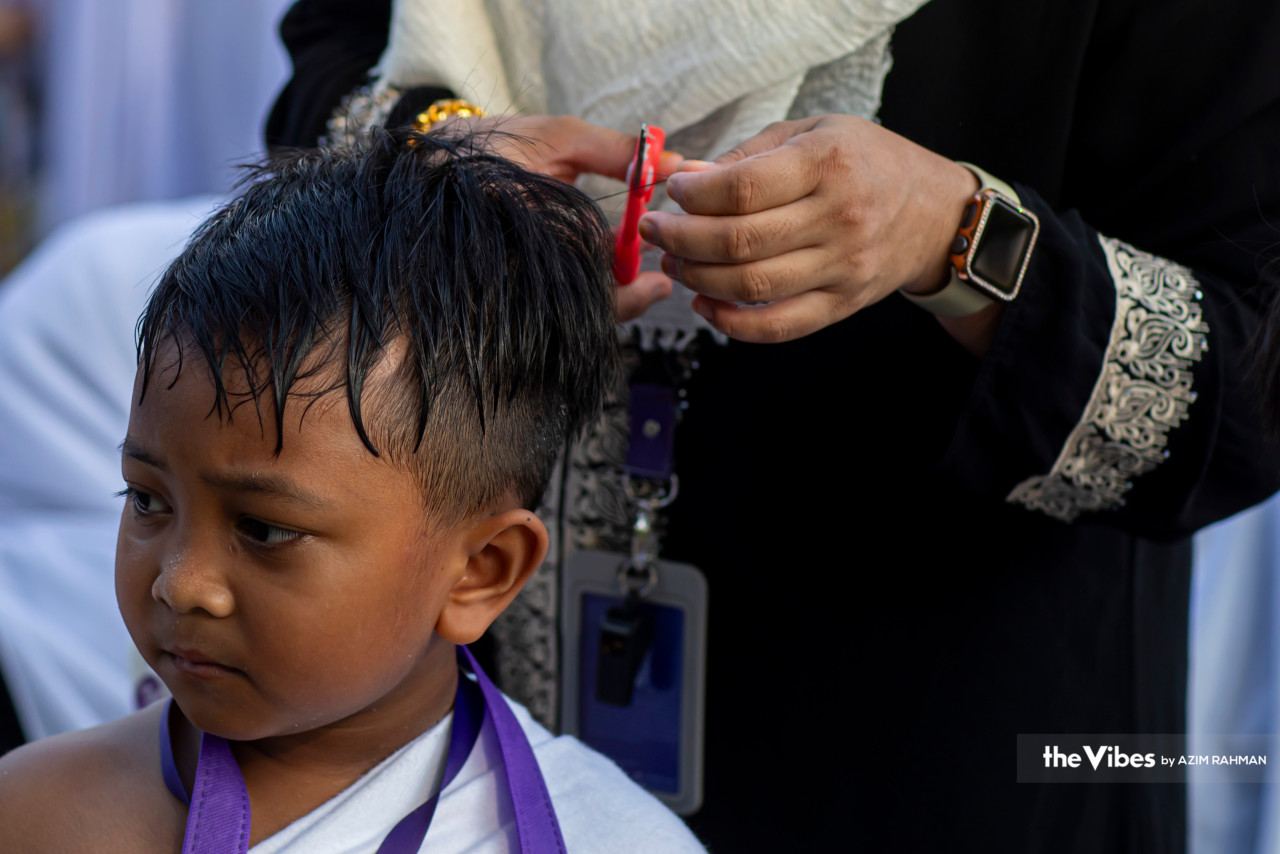 A boy learns about one ritual haj pilgrims will undergo, which is the cutting or shaving of one’s hair. – AZIM RAHMAN/The Vibes pic, June 24, 2023