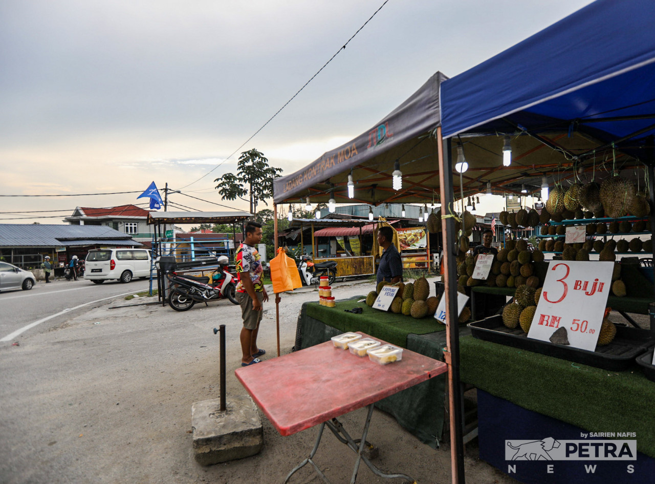 A man is talking to a durian seller in Paya Jaras. Locals say the poor state of the economy has forced many residents to run small-scale businesses in order to sustain a living. – SAIRIEN NAFIS/The Vibes pic, November 10, 2022