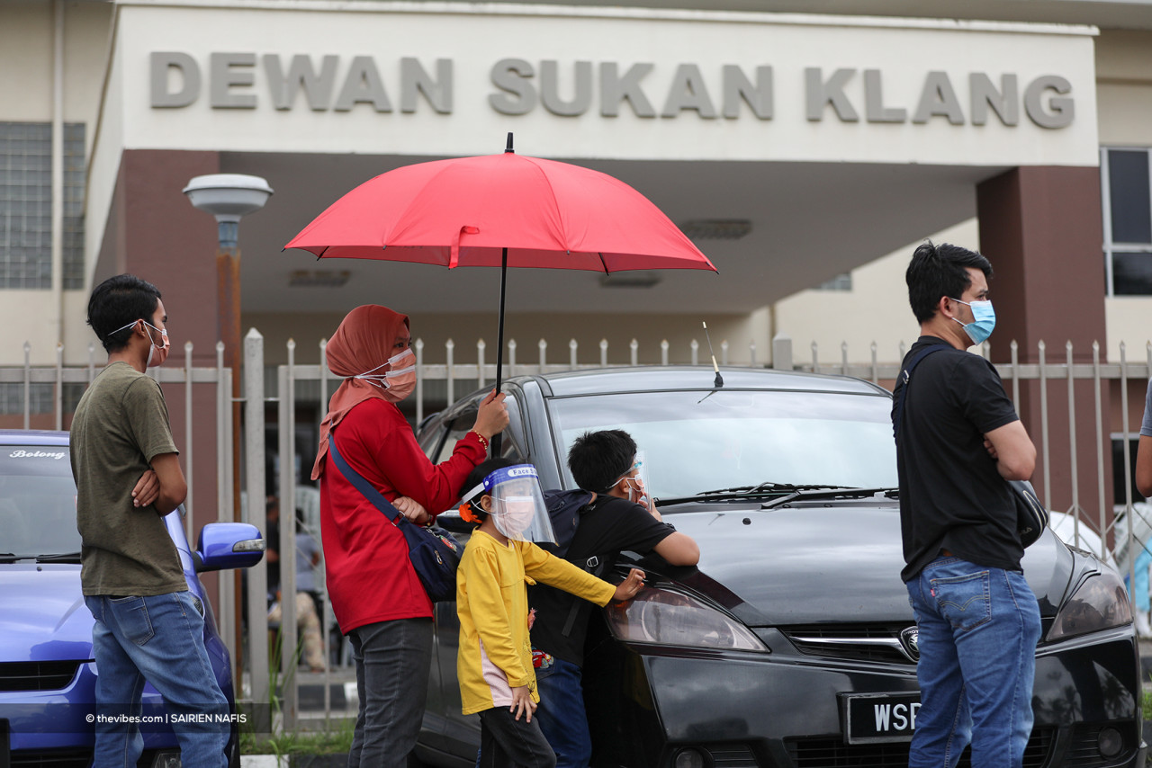 Families wait in line just outside the Klang Sports Hall. – SAIRIEN NAFIS/The Vibes pic, July 13, 2021
