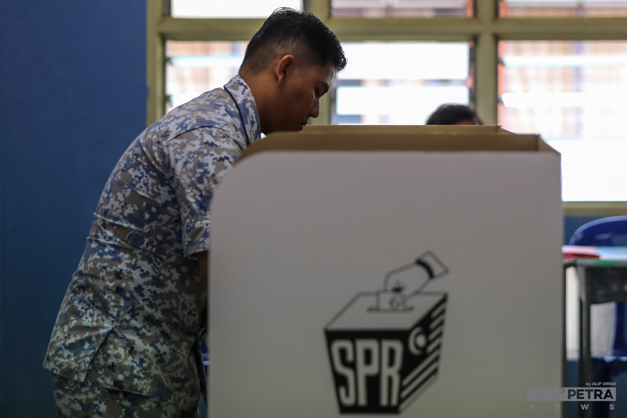 A Royal Malaysian Navy officer casts his early vote in one of the ballot boxes at SMK Pangkalan TLDM Lumut, Perak polling centre today, along with other eligible early voters in the nation for the 15th general election. – ALIF OMAR/The Vibes pic, November 15, 2022