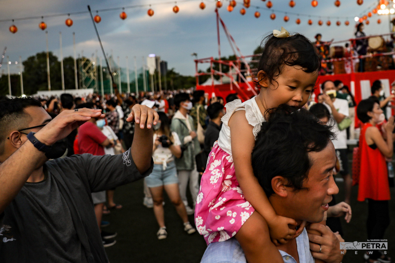 A child piggy-backing on her father in the crowd during the Bon Odori Festival. – SAIRIEN NAFIS/The Vibes pic, July 18, 2022