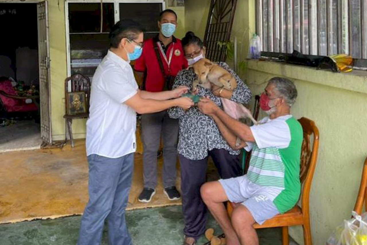 Pasir Bedamar assemblyman Terence Naidu (left) gives N. Marimuthu Naidu aid, as A. Vimala holds Anandaveli in her arms. – The Malay Mail pic courtesy of Terence Naidu, June 24, 2021