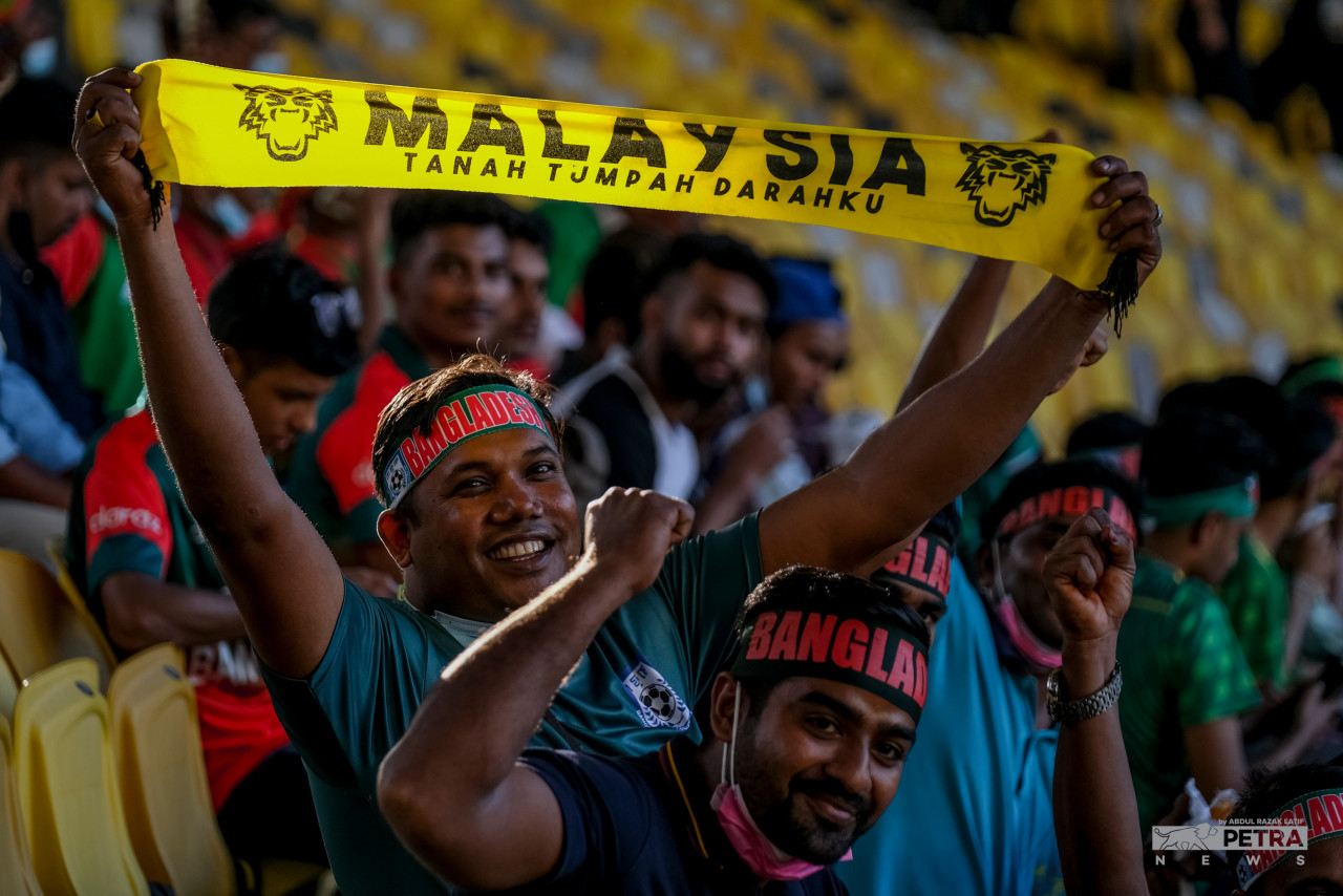 A Bangladesh fan holds aloft a Harimau Malaya banner in Bukit Jalil National Stadium ahead of the big game. – ABDUL RAZAK LATIF/The Vibes pic, June 14, 2022
