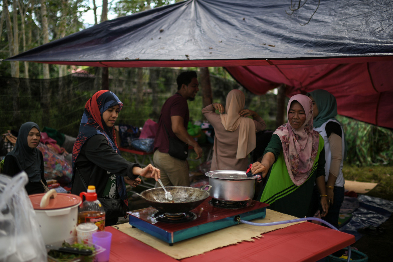 Kg Iboi resident Norhayati Ismail, 38, (left) and her family prepare food at a temporary campsite, nearby her house that was destroyed in last Monday’s floods. – Bernama pic, July 10, 2022