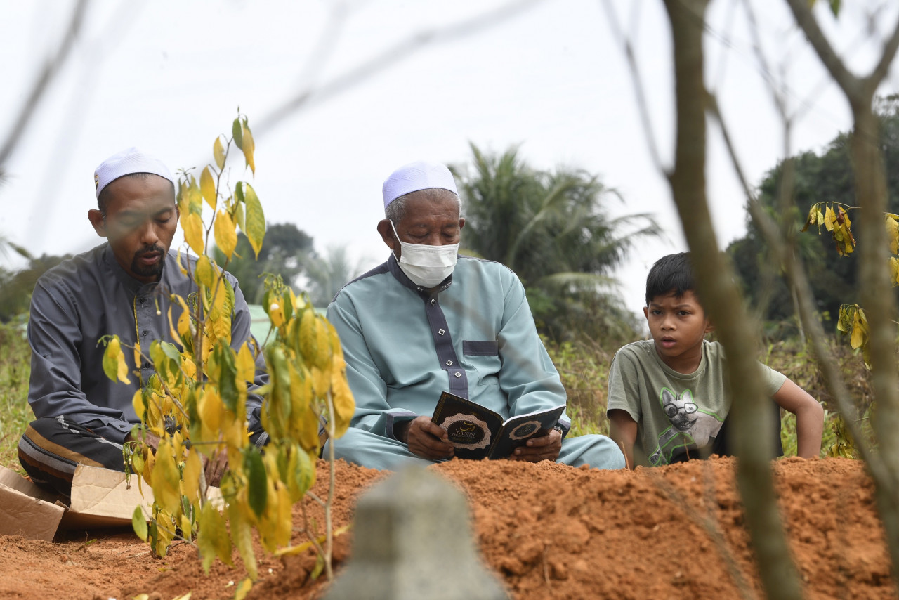 Kg Iboi resident Abd Rahman Said, 71, (centre) visits the graves of the family members he lost in last Monday’s Baling floods, at the Kg Charuk Bemban Dalam Muslim Cemetery in Baling. – Bernama pic, July 10, 2022