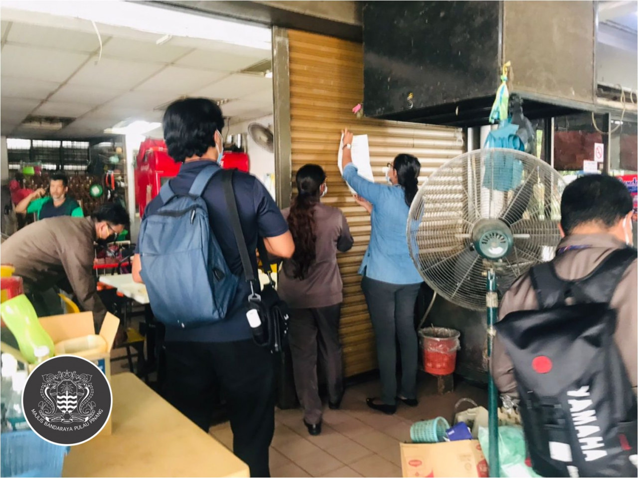 Penang Island City Council personnel place a notice on the entrance of one of the eateries raided and found to be practising poor hygiene. – Majlis Bandaraya Pulau Pinang - MBPP Facebook pic, July 28, 2022