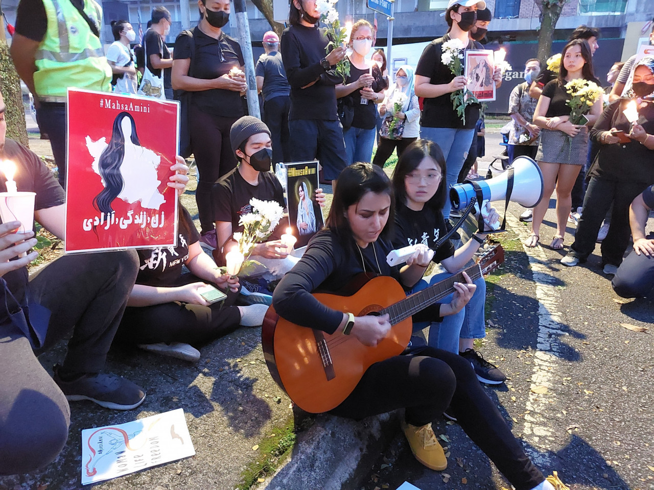 One Iranian female attendee at the candlelight vigil for the slain Mahsa Amini, who only wishes to be identified as Simin (holding guitar), sings a Persian protest song, which she says ‘is dedicated to people who are dying’ in Iran. – A. AZIM IDRIS/The Vibes pic, September 25, 2022