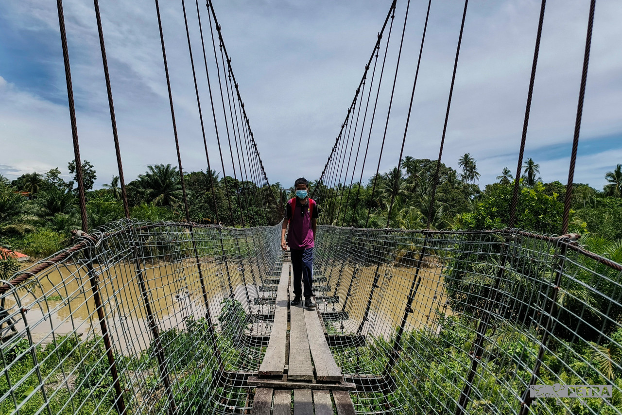 A Primary Six student crossing the dilapidated bridge to get home from his school in SK Sibuga Besar. – REBECCA CHONG/The Vibes pic, October 4, 2022