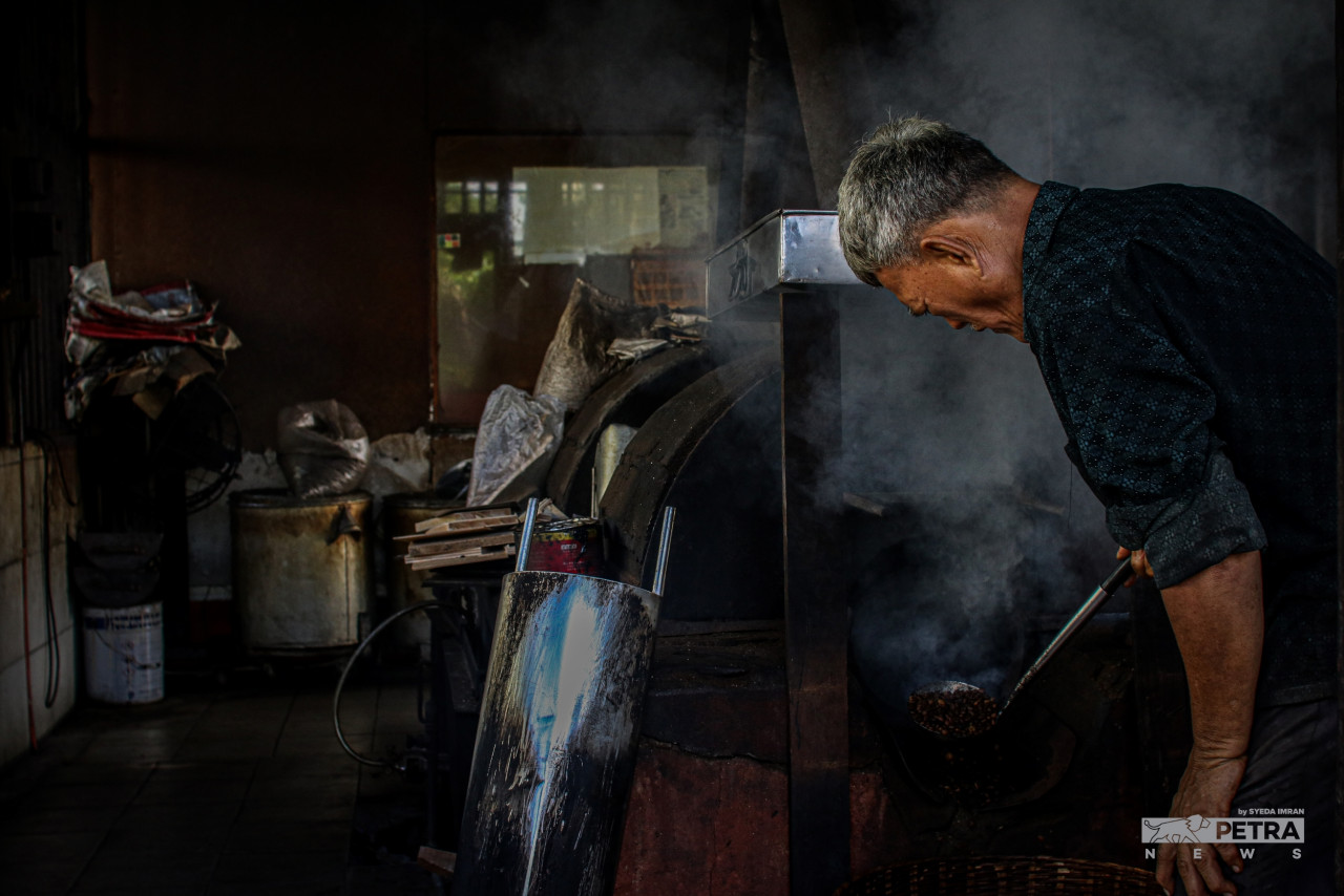 Tan checks the coffee beans during the roasting process. He maintains the traditional charcoal method of roasting. – SYEDA IMRAN/The Vibes pic, October 1, 2022