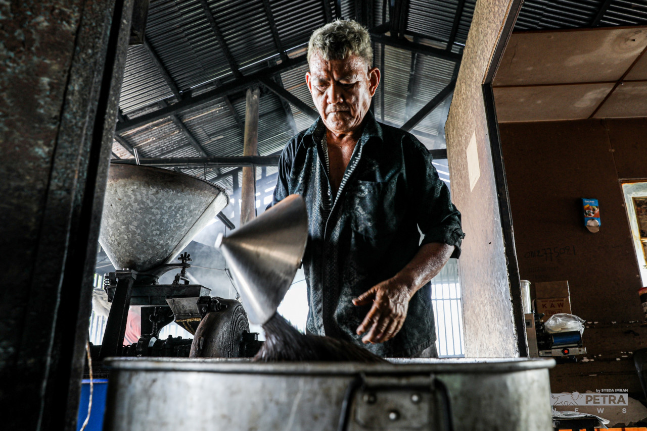 Tan pours the caramelised coffee beans into a blending machine for the grinding process, where the beans are turned into coffee powder. – SYEDA IMRAN/The Vibes pic, October 1, 2022