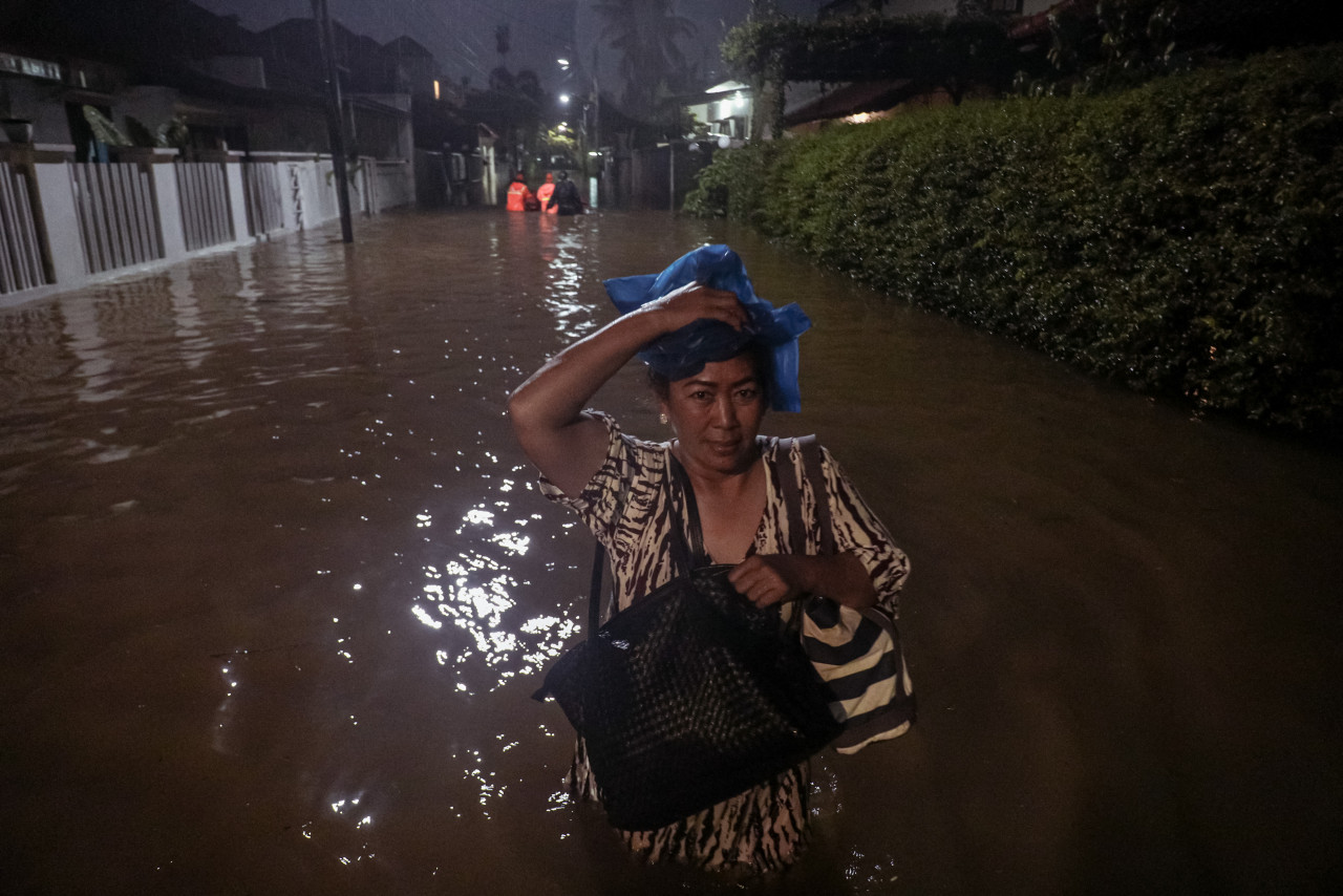 A woman making her way through a street flooded due to heavy rain in a residential area in Jakarta on Thursday. Jakarta has faced large-scale severe flooding repeatedly over the past three decades, most recently in 2020. – AFP pic, October 8, 2022