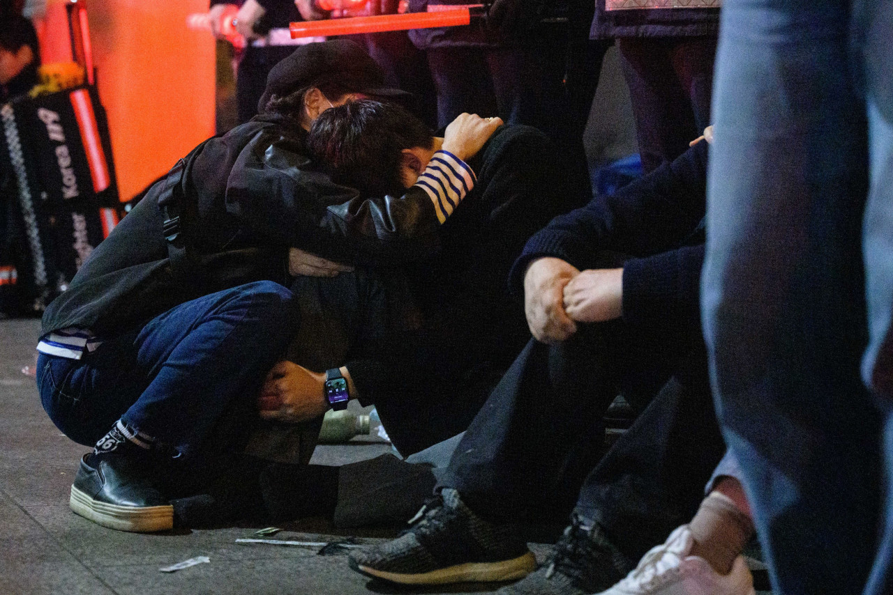 Dazed passers-by sit on the sidewalk, checking their phones, while others comfort themselves, hugging each other. – AFP pic, October 30, 2022 