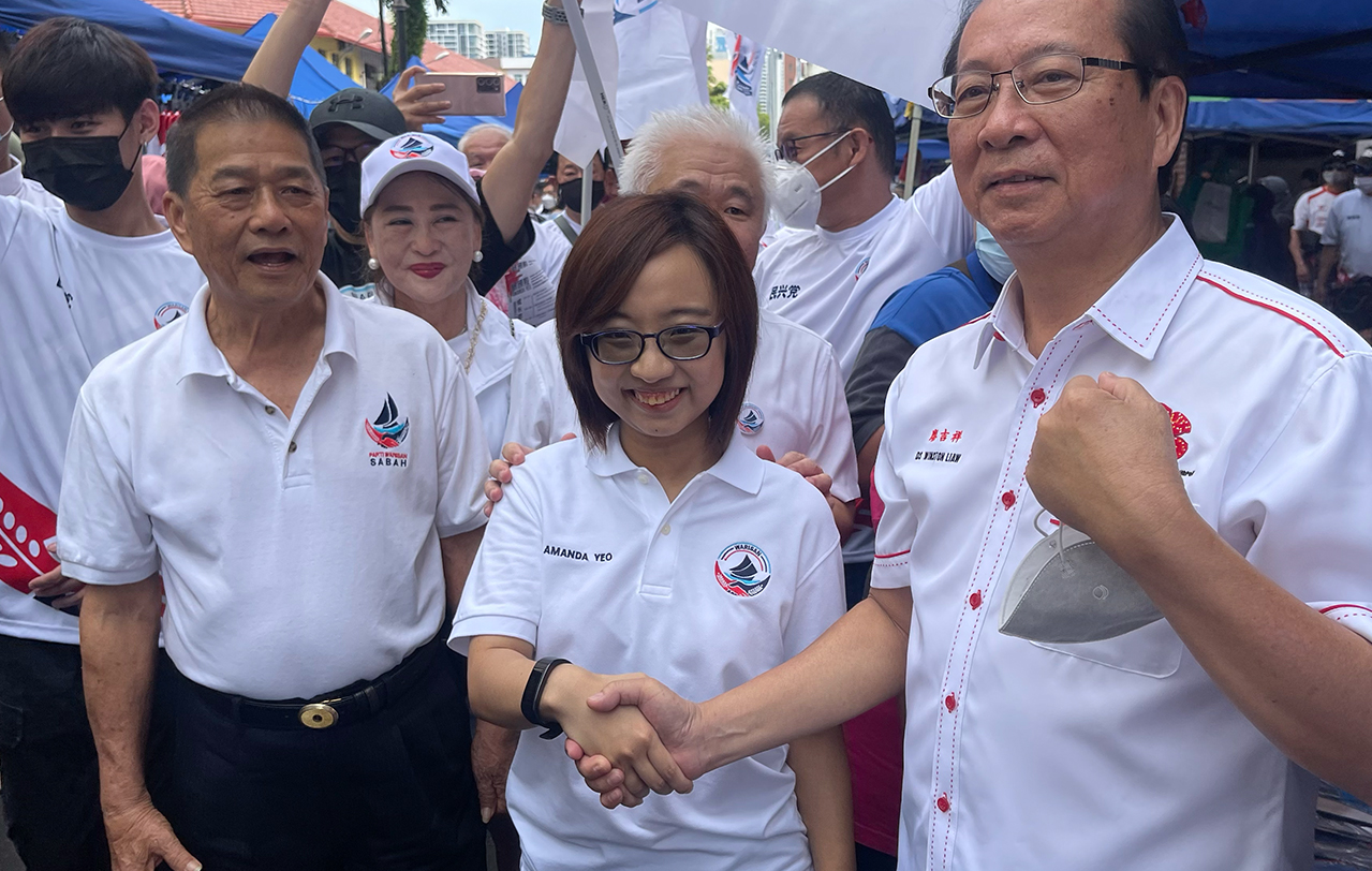 Warisan Kota Kinabalu candidate Amanda Yeo (centre) shakes hand with her opponent from Parti Kesejahteraan Demokratik Masyarakat, Datuk Winston Liaw (right) as they both conduct their walkabouts today at Gaya Street Fair after being nominated as candidates yesterday. – JASON SANTOS/The Vibes pic, November 6, 2022 