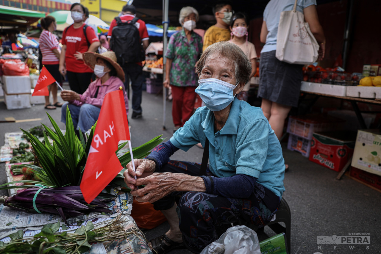 Vegetable sellers at the Bentong morning market in Pahang clutch Pakatan Harapan (PH) flags. The Bentong parliamentary constituency will see DAP’s Young Syefura Othman attempt to defend the seat for PH. – SYEDA IMRAN/The Vibes pic, November 10, 2022