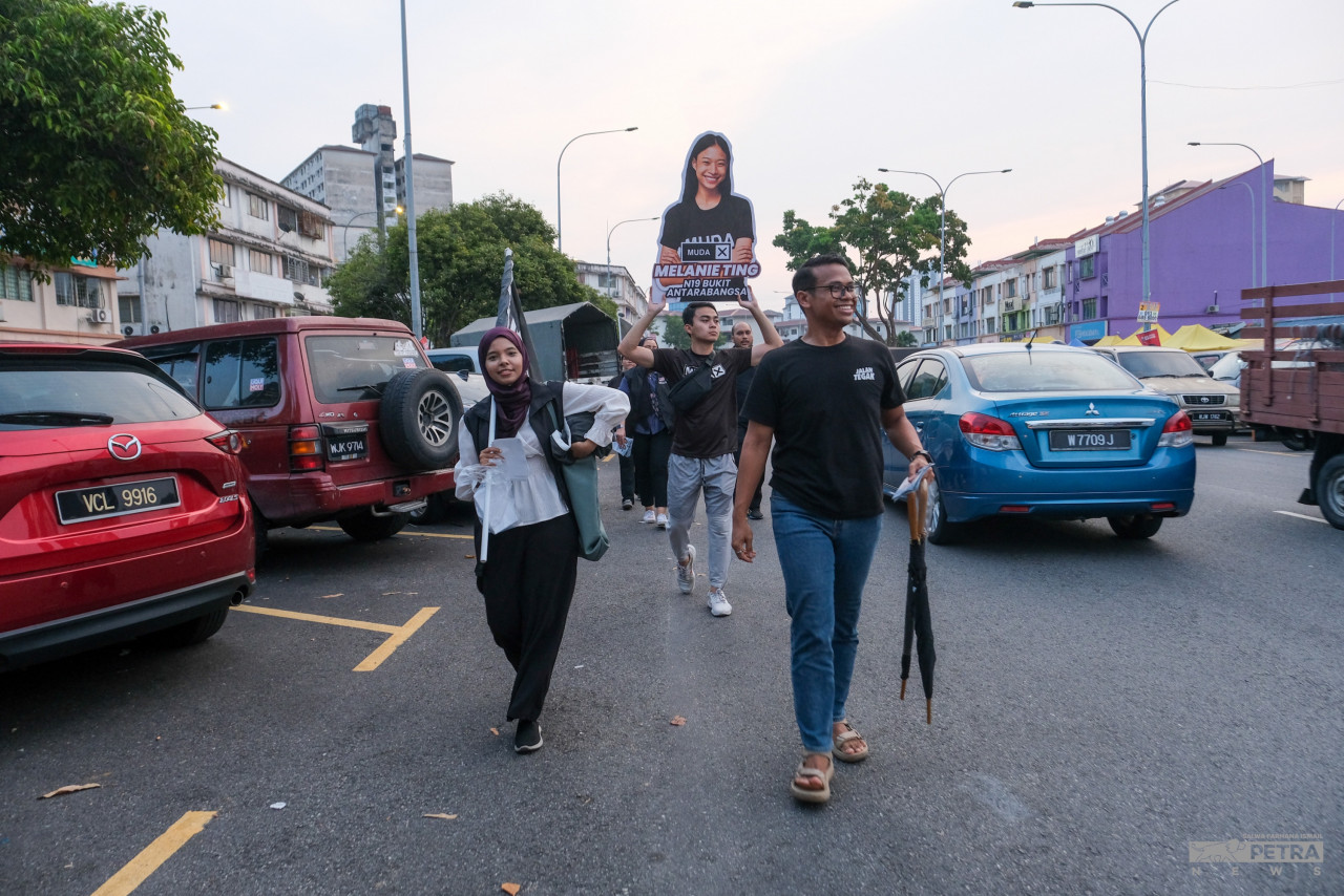 Muda party members on the campaign trail for Melanie Ting, carrying a large cutout of her on the streets of Bukit Antarabangsa. – SALWA FARHANA ISMAIL/The Vibes pic, August 8, 2023